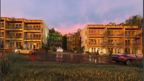 A row of townhomes with Porsches around them on a busy road. 