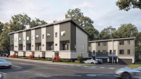 A row of white and gray townhomes under construction on a busy road in Atlanta. 