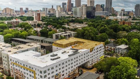 A large apartment project being built with a city in the distance behind it. 