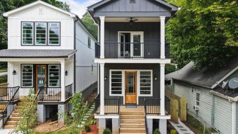A white and dark grey houses in Atlanta with green lawns and small trees in front. 