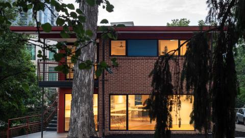 A photo of a brick office building turned into apartments near large trees in Atlanta. 