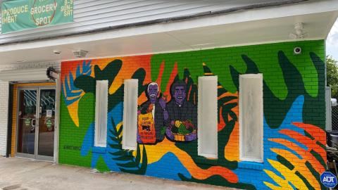 A colorful exterior of a grocery store in Atlanta, under blue skies, with two guys painted on front. 