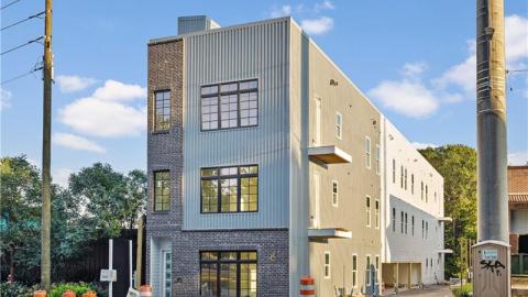 A photo of a small condo building with green trees all around it. 