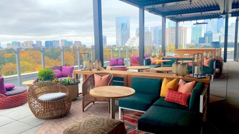 A view of a hotel rooftop over Atlanta with many colorful fall trees beyond. 