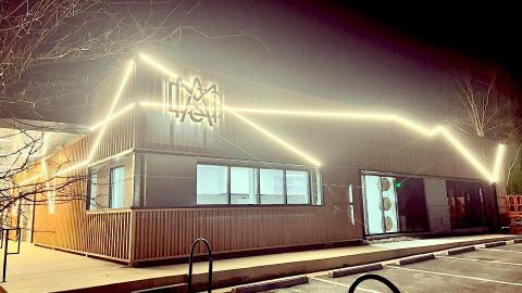 A photo of a former warehouse with huge lights on it at night. 