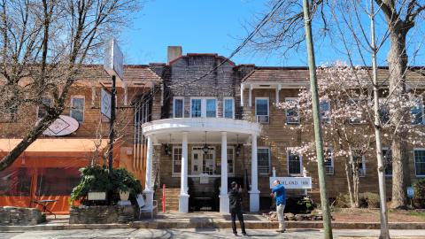Exterior photo of an old hotel building and retail next to it in Atlanta under blue skies. 