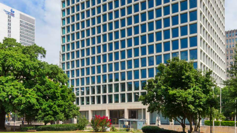A glass and concrete office building in downtown surrounded by other buildings, with a cafe and offices in renderings. 