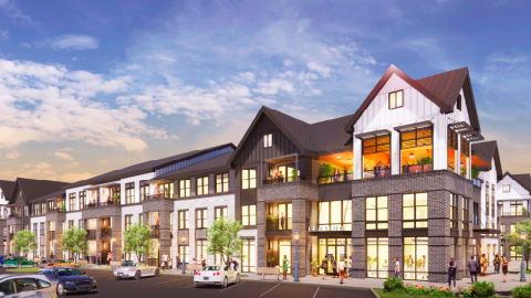 An image of a multifaceted new development under blue skies with many parking lots all around and brick and white buildings. 