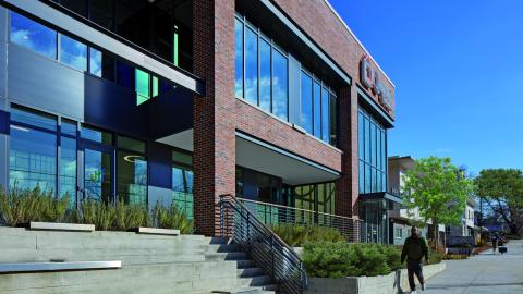 A photo of a large brick office building surrounded by new mixed-use development under blue skies in Atlanta. 
