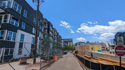 A photo of a large apartment complex under construction with a stadium in the distance. 