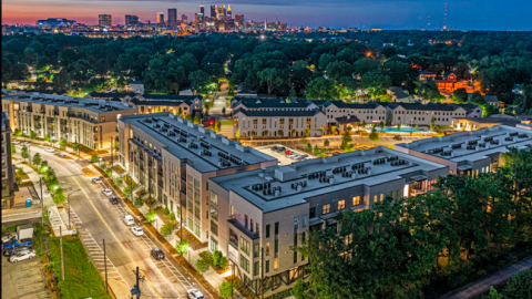An overview of a new white and stone apartment and townhome complex under clear skies in Atlanta. 