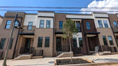 A photo of a brown and brick townhome community being built under blue skies in Atlanta. 