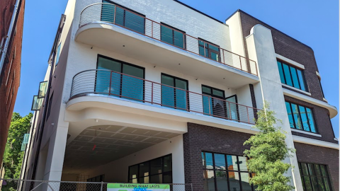 A photo of a brick building under blue skies that's white and brown with curved balconies.