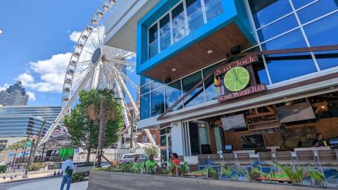 A photo of a beachy blue restaurant with palm trees in downtown Atlanta under a blue sky.