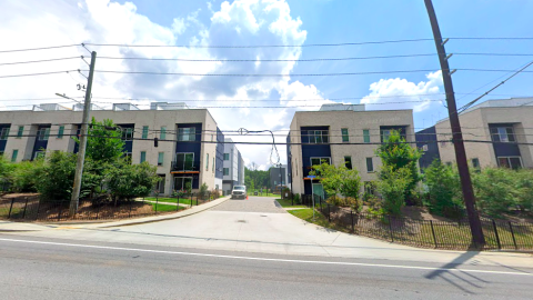 A photo of a large brick-fronted townhomes with modern white interiors on a busy street.