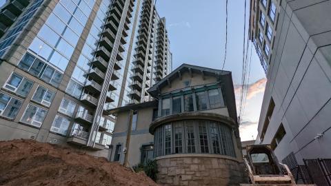 An old home surrounded by tall glassy buildings under bluish purple skies in Midtown Atlanta. 