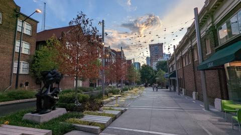 A new plaza under a sunset in Midtown Atlanta with yellow seating and a statue. 