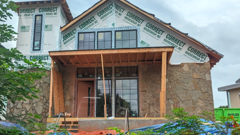 An old stone church that's being remade into a duplex dwelling with a new facade, windows, and porches. 