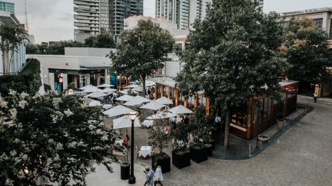 A photo of a shopping district with many trees and glassy buildings under gray skies in Atlanta.