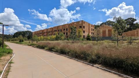 A photo of a large wooden framed building under blue skies near many trees.