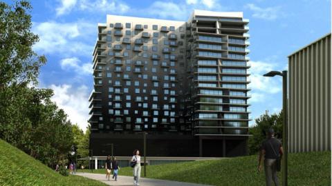 A large grey, black, and white building under blue skies along a walking path in Atlanta. 