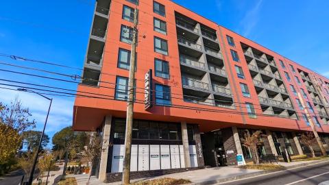 A photo of a large red apartment building under blue skies on a corner in Atlanta.