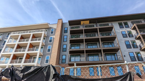 A photo of a large apartment complex being built under blue skies in Atlanta, near a dusty wide path.