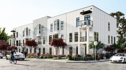 A rendering showing a new community with white and gray buildings under blue skies with blooming red trees nearby. 
