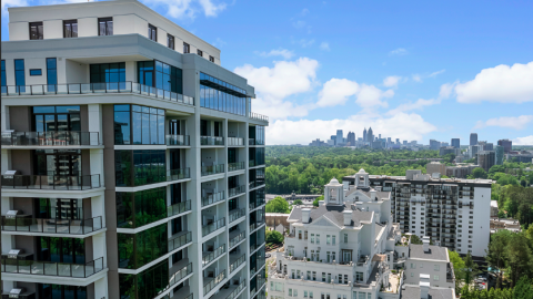 A photo of a large white condo building with much glass under blue skies. 
