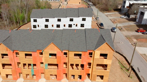 A large development site in Atlanta where apartments are being built next to many trees an new houses.
