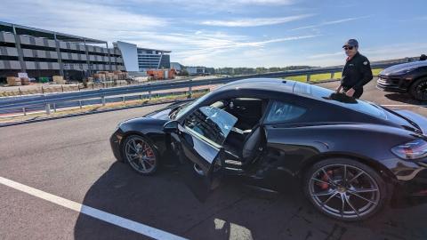 A photo of a new racetrack with many Porsche cars under blue skies near modern new buildings.
