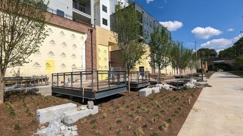 A development building with yellow construction material over large windows next to a wide trail and tunnel in Atlanta.