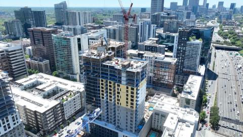 An aerial photo of a large new apartment tower with a red crane adhered to it. 