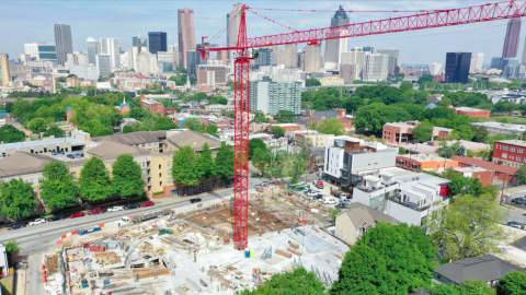 An aerial photo of a long street dotted with new buildings with a huge city skyline in the distance. 