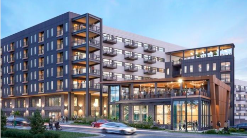 A rendering showing a new stack of apartments with a side building for retail along a busy road, under blue skies. 
