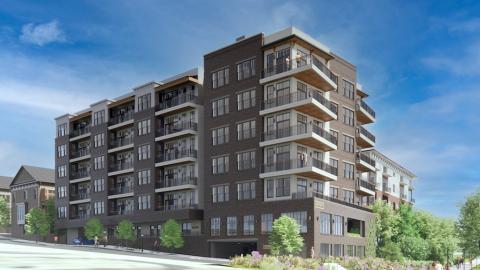 An image showing a boutique condo building with brick and glass and large balconies beside a large walking path. 