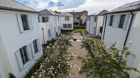 A photo of a row of new housing in a newly built town under blue cloudy skies. 