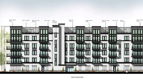 An image of a white and black condo building under gray skies near trees.