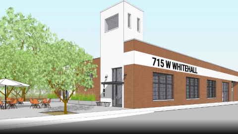 An image of an old brick warehouse remade into studios next to a wide street and railroad tracks in Atlanta.