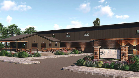 An image showing where a brick and brown long low events center is coming next to a large parking lot.