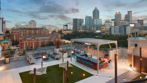 A photo of a large red and gray student housing tower near downtown Atlanta with a pool on the roof and modern interiors.