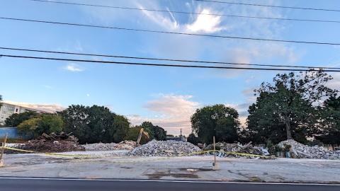 An image showing a large development site on a corner near a blacktop road under blue skies where a large mixed-use project is being built.