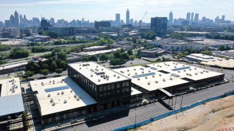An aerial photo of a large warehouse turned into offices and restaurants with large windows and brick facade.