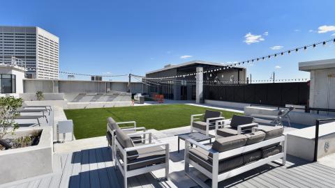 An image of a large concrete and siding apartment complex with white walls inside and a greenspace on the roof. 