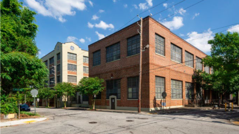 A photo of a brick building under blue skies that's white and brown with curved balconies.