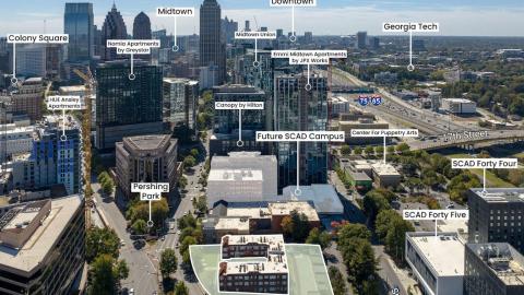 An image of a large old brick apartment building in the middle of Atlanta with large streets and skyscrapers around it.