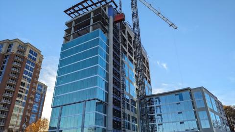 Image showing a large apartment tower made of glassy with a shorter glassy building beside it overlooking a wide street in a busy Atlanta neighborhood.
