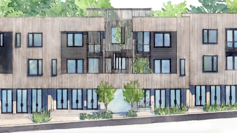 An image of a site near tall trees with a modern building with four units is being built near woods and traditional white homes.