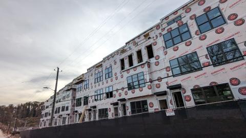 A photo of a large new townhome project under gray skies near a wide road in Atlanta.