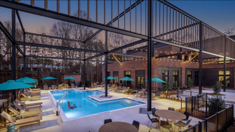 A photo of an office and apartment complex remade from an old office building with brick walls and a large pool and modern white interiors.